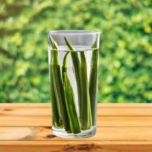 A glass of okra water with sliced okra on a table